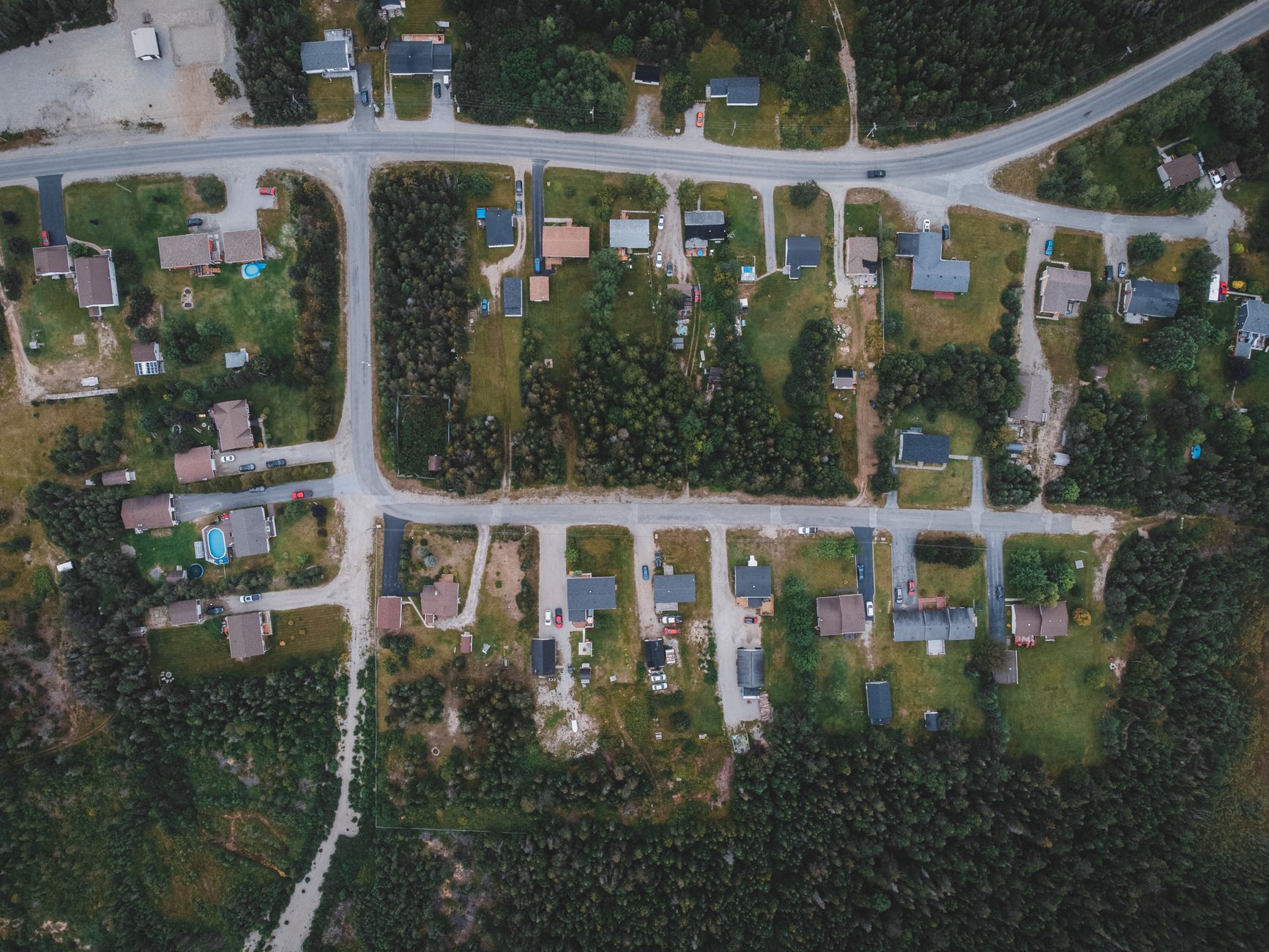 Flygfoto över korsning med rondell, vägar, bilar och omgivande byggnader och grönområden.